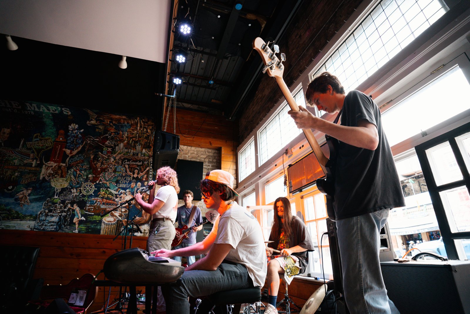Finn Dickens on keys with the band at Maggie Mae's, mural of Austin music history on the wall