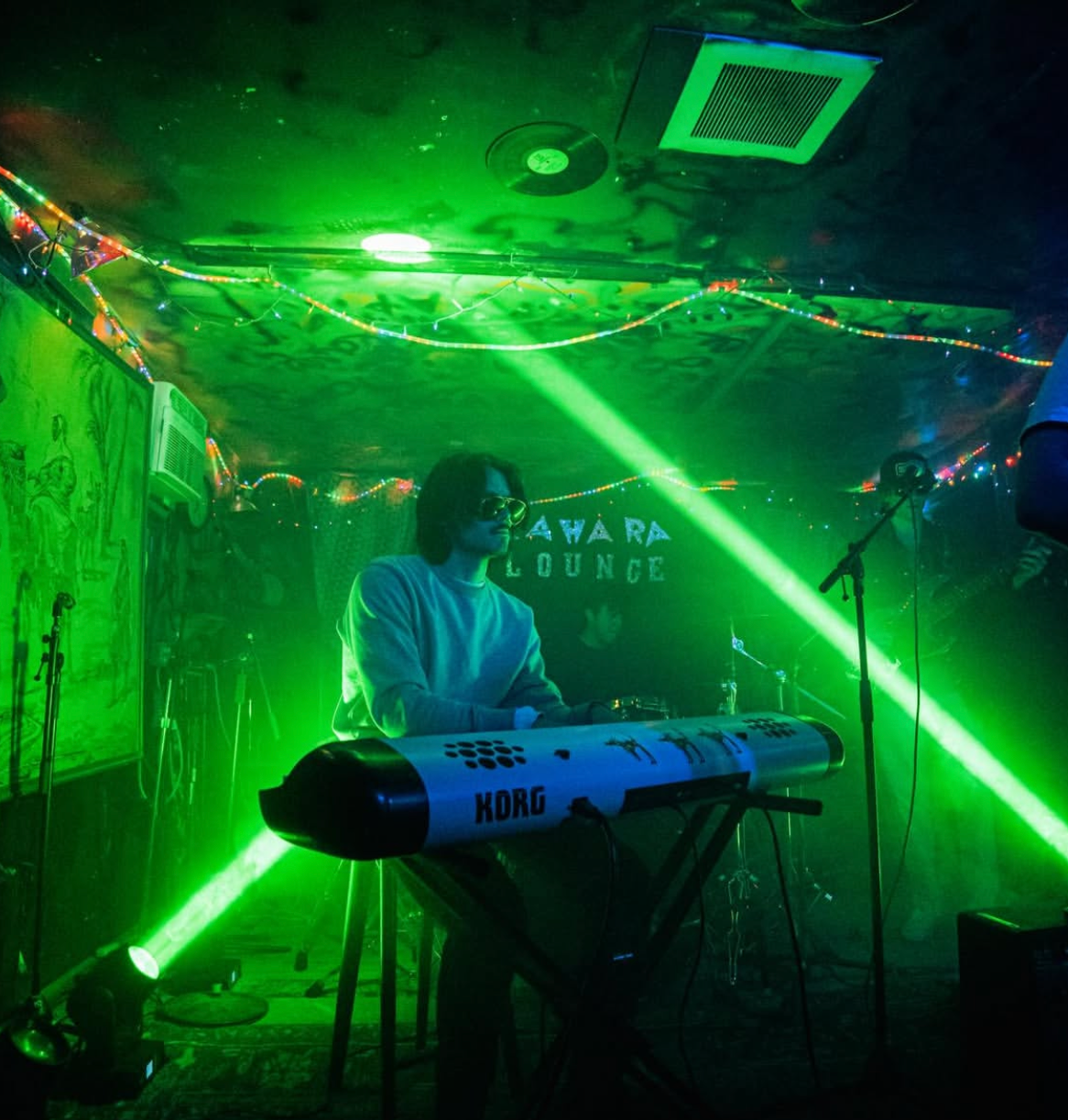 Finn Dickens at the keys under a green laser at Sahara Lounge
