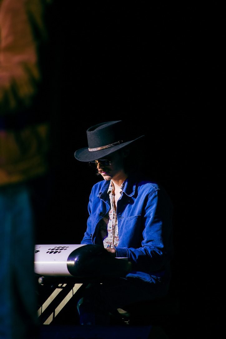 Finn Dickens in a blue jacket, lit by a single spotlight at the keys